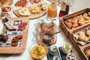 Diversos productos alimenticios, como quesos, embutidos y pasteles, sobre una mesa.