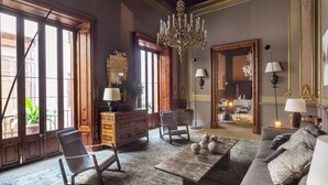 Un salón amplio con candelabro, sofá, mesa de centro y chimenea.
