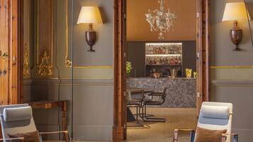 A bar area with a marble countertop, bar stools, and a selection of bottles.