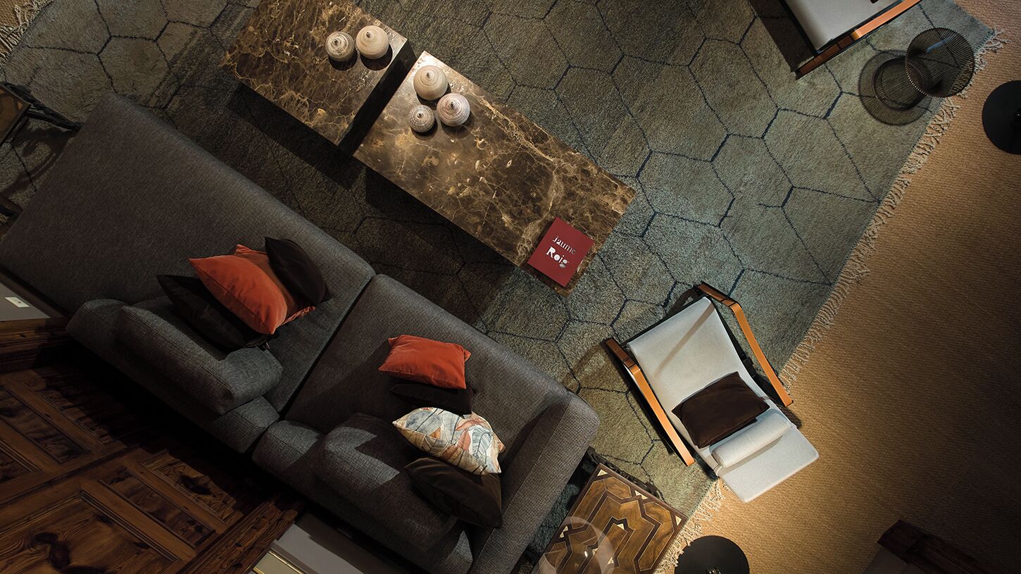 Un salon moderne avec un canapé gris, une table basse à motifs et un fauteuil.