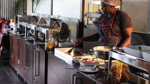 Buffet montado com várias estações de comida e uma pessoa servindo.