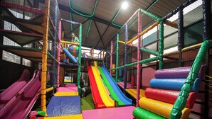 Espaço de recreação infantil com vários escorregadores e áreas de piso acolchoado.