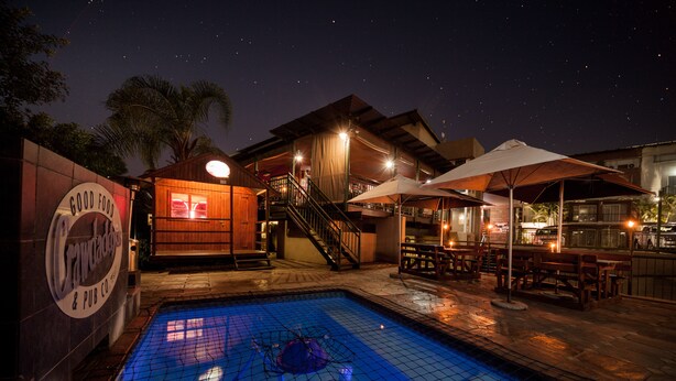 Área de piscina com piscina cercada por rede, deck de madeira e mobiliário para área externa.
