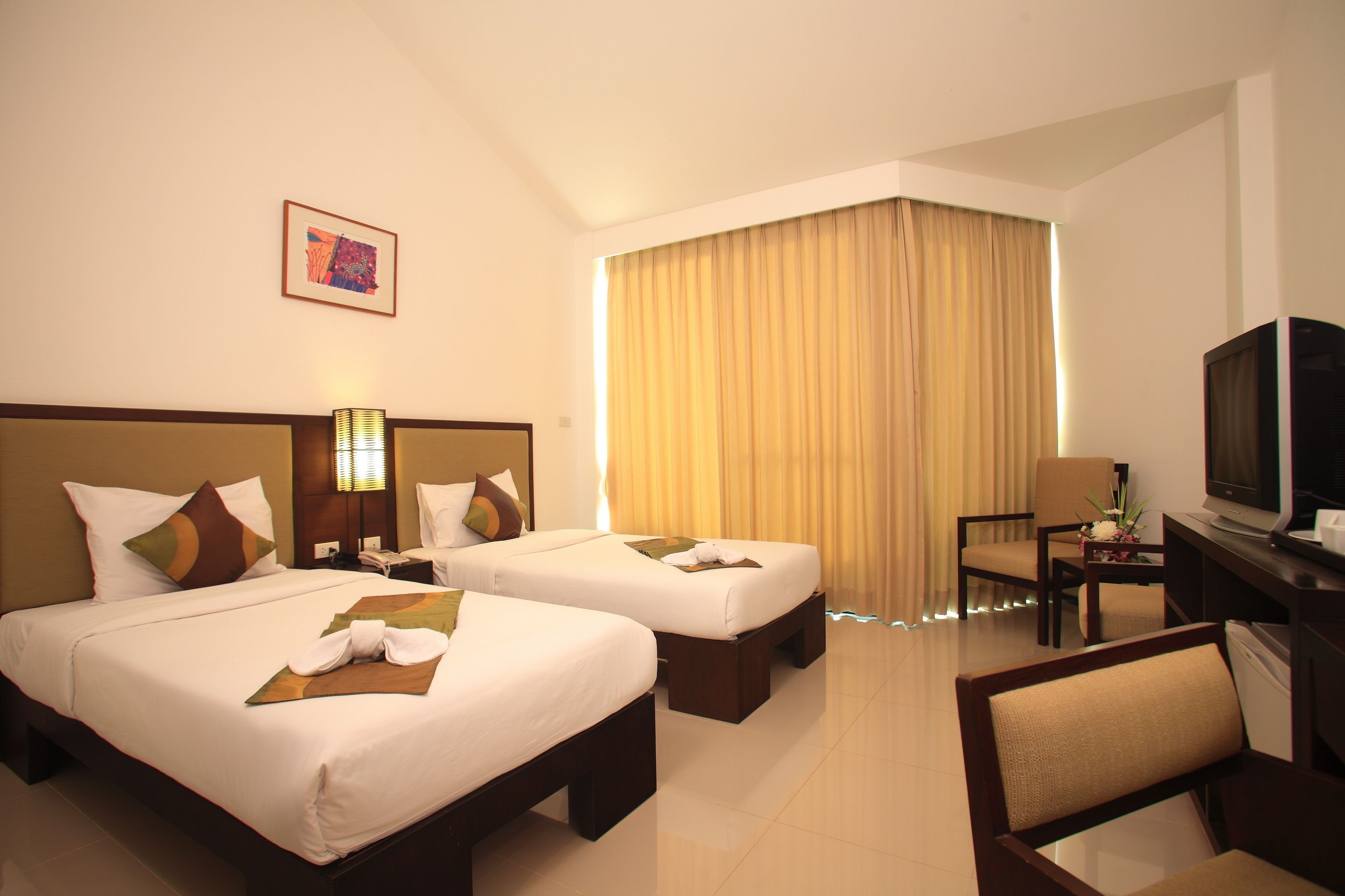 A hotel room with two beds, a TV, a desk, and a chair.