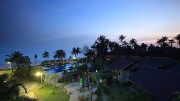 Un resort con piscina, palmeras y senderos bien iluminados.