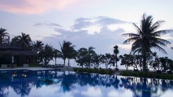 Relax by the tranquil pool surrounded by lush vegetation and palm trees.