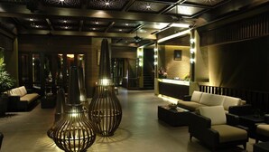 A lobby with modern furniture, a reception desk, and decorative lighting fixtures.
