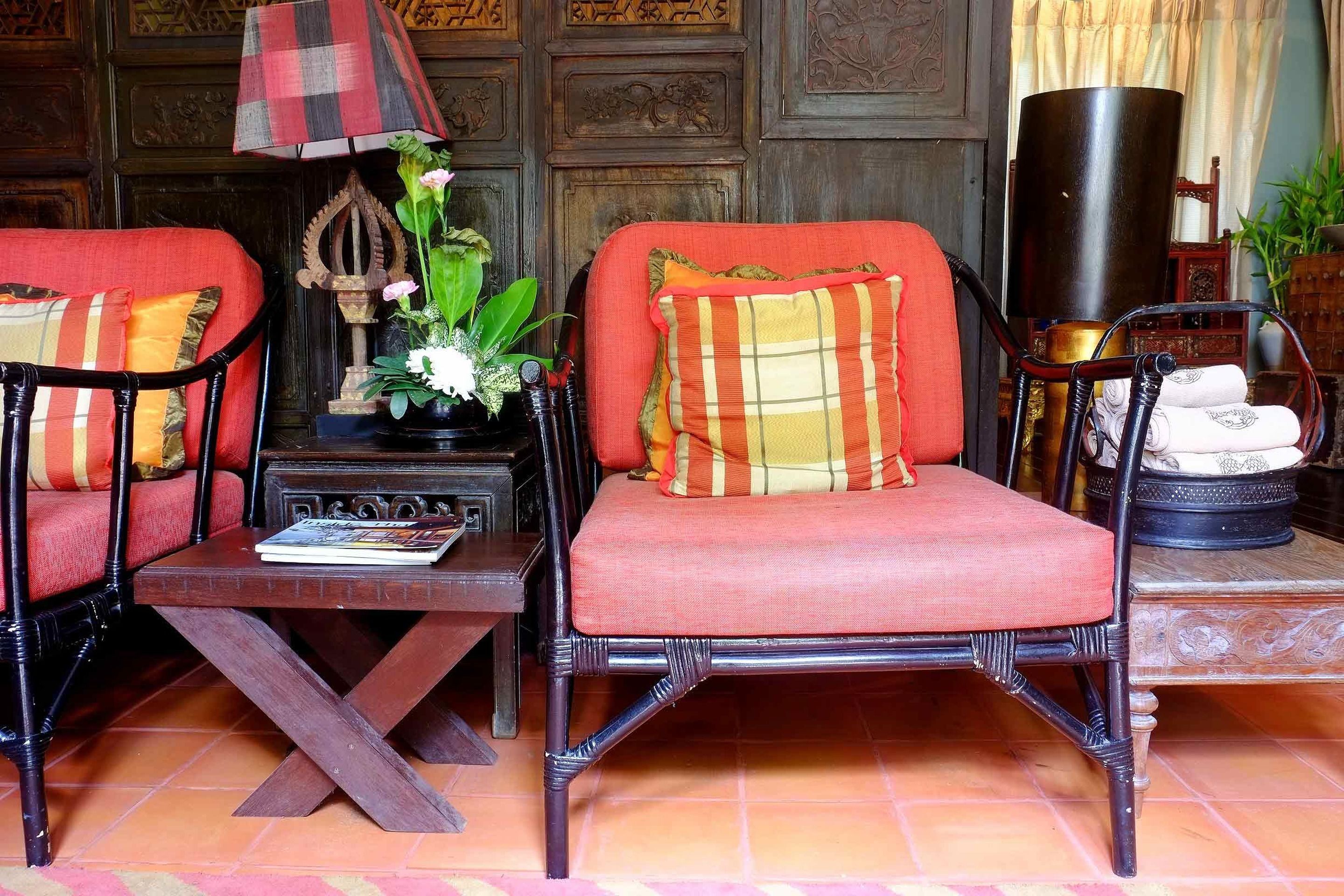 Una habitación con dos sillones de mimbre, una mesita con una revista y una lámpara decorativa.