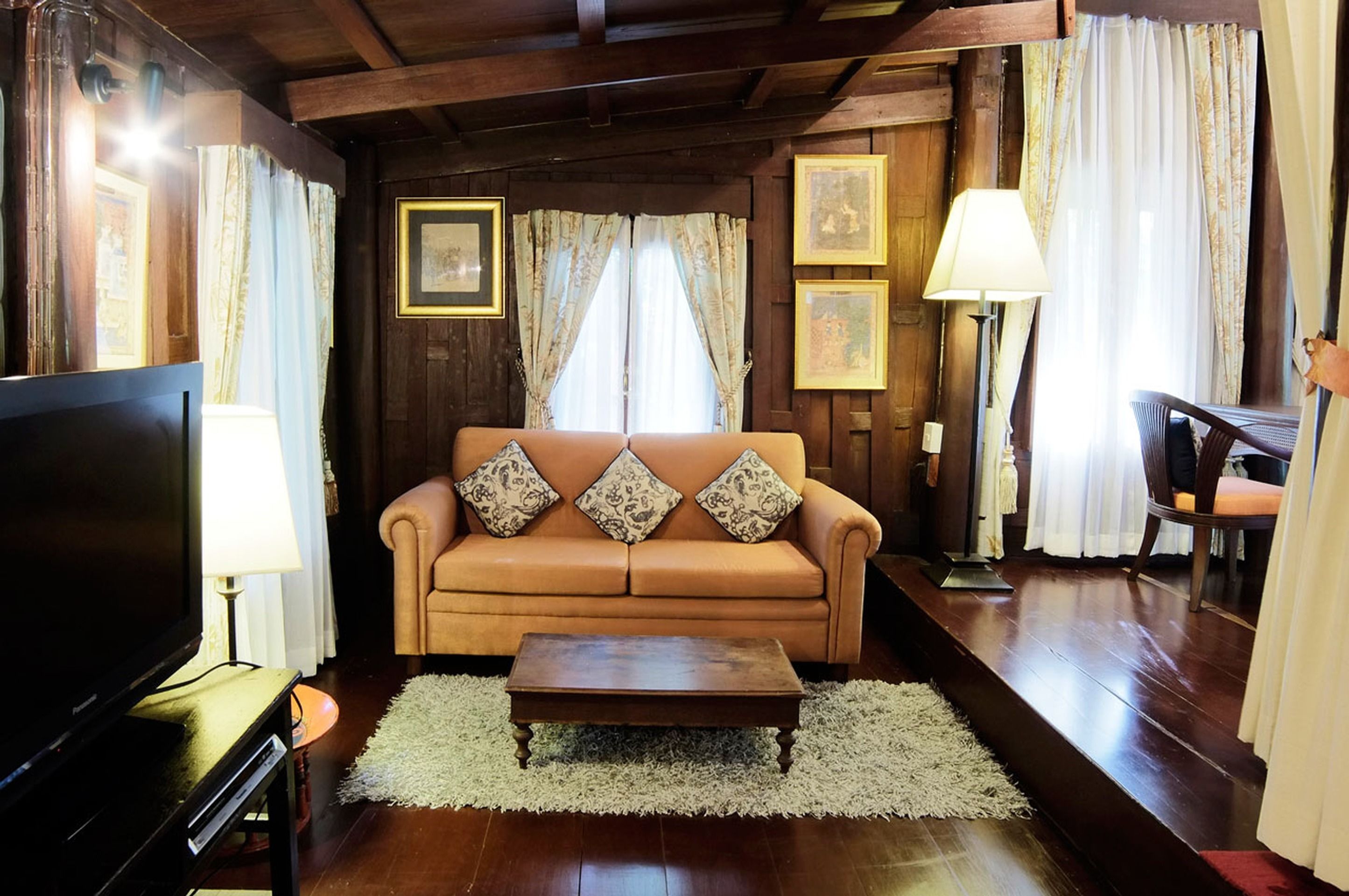A cozy living room with a brown leather sofa, a wooden coffee table, and a flat-screen TV.
