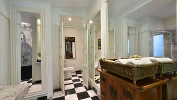 Un baño con piso a cuadros, un aparador de madera y un espejo grande.