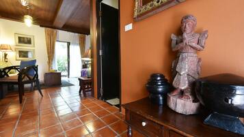 Una habitación con suelo de baldosas, una mesa de madera, una estatua y un espejo en la pared.