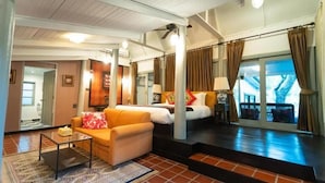A hotel room with a sofa, a bed, a coffee table, and a view of the outside. - Zantiis Ndol Villas (Muak Lek)