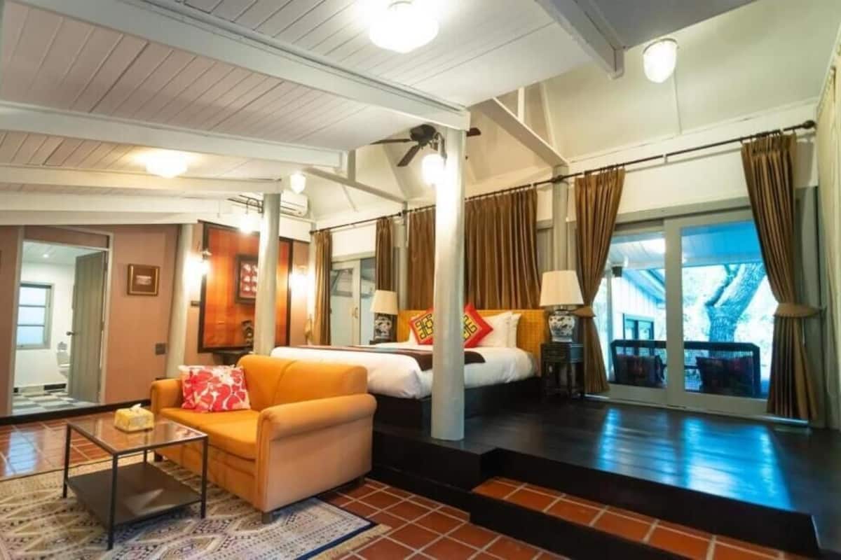 A hotel room with a sofa, a bed, a coffee table, and a view of the outside.