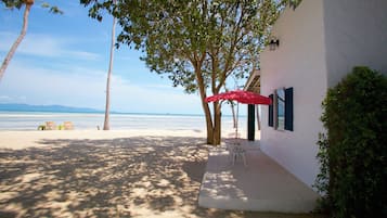 Una propiedad frente a la playa con un patio, una sombrilla roja y vistas al mar.