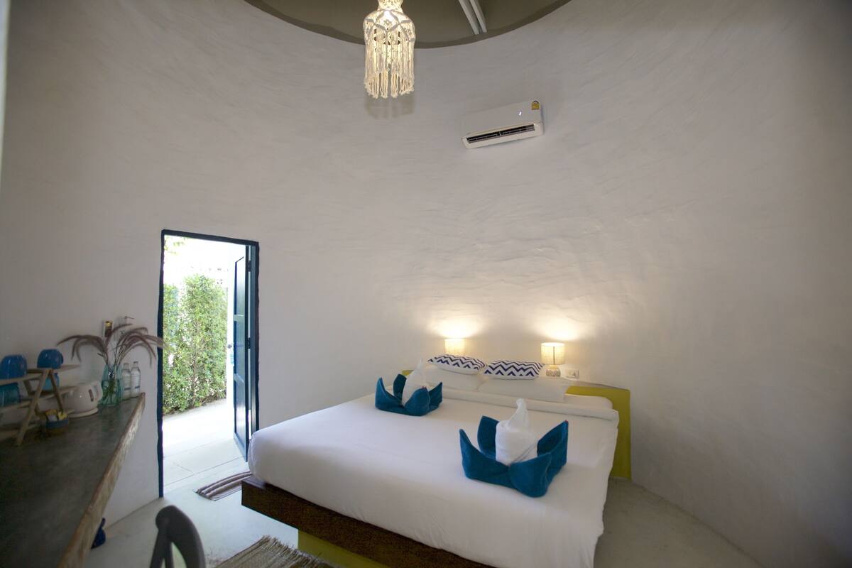 Ein Schlafzimmer mit einem Bett, Nachttischlampen, einer Deckenleuchte und einer Tür zu einem Außenbereich.