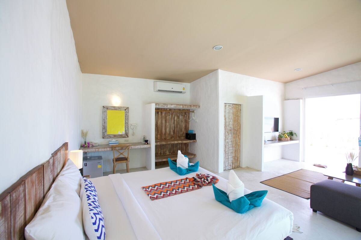 Ein Hotelzimmer mit Bett, Schreibtisch, Kleiderschrank und Blick ins Freie.
