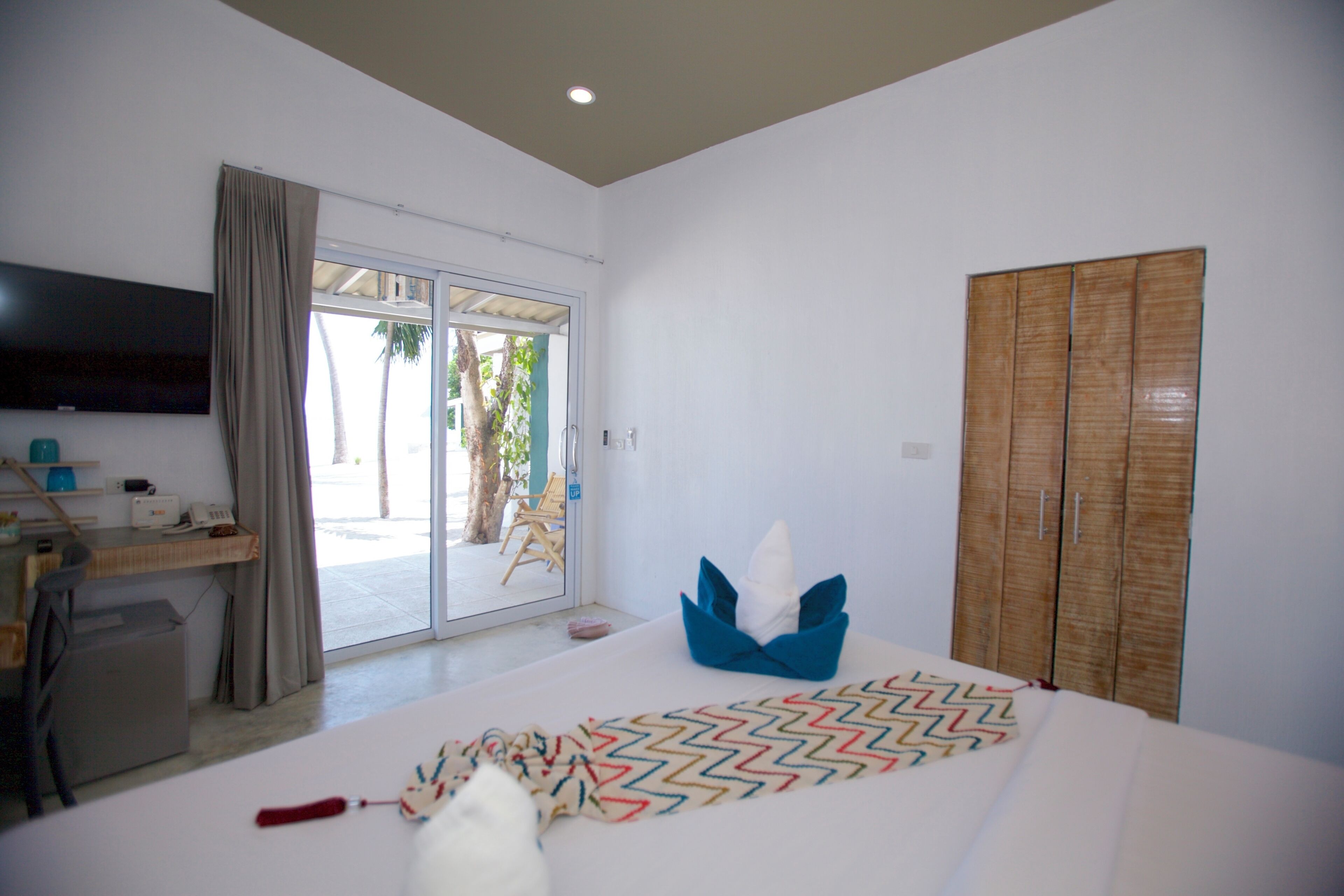 A hotel room with a bed, a desk, a television, and a wardrobe.