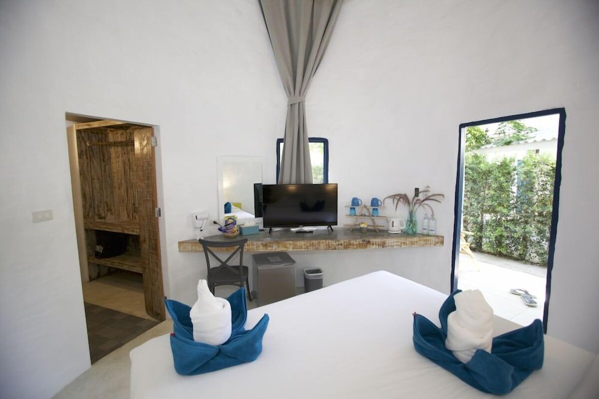 A room with a bed, a TV, a small table, and a window.