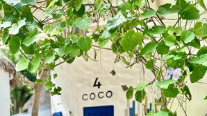 A white building with a blue door labeled "4 COCO" and a red and white striped beach chair outside. - Lime & Soda Beachfront Resort (Ko Pha-ngan)