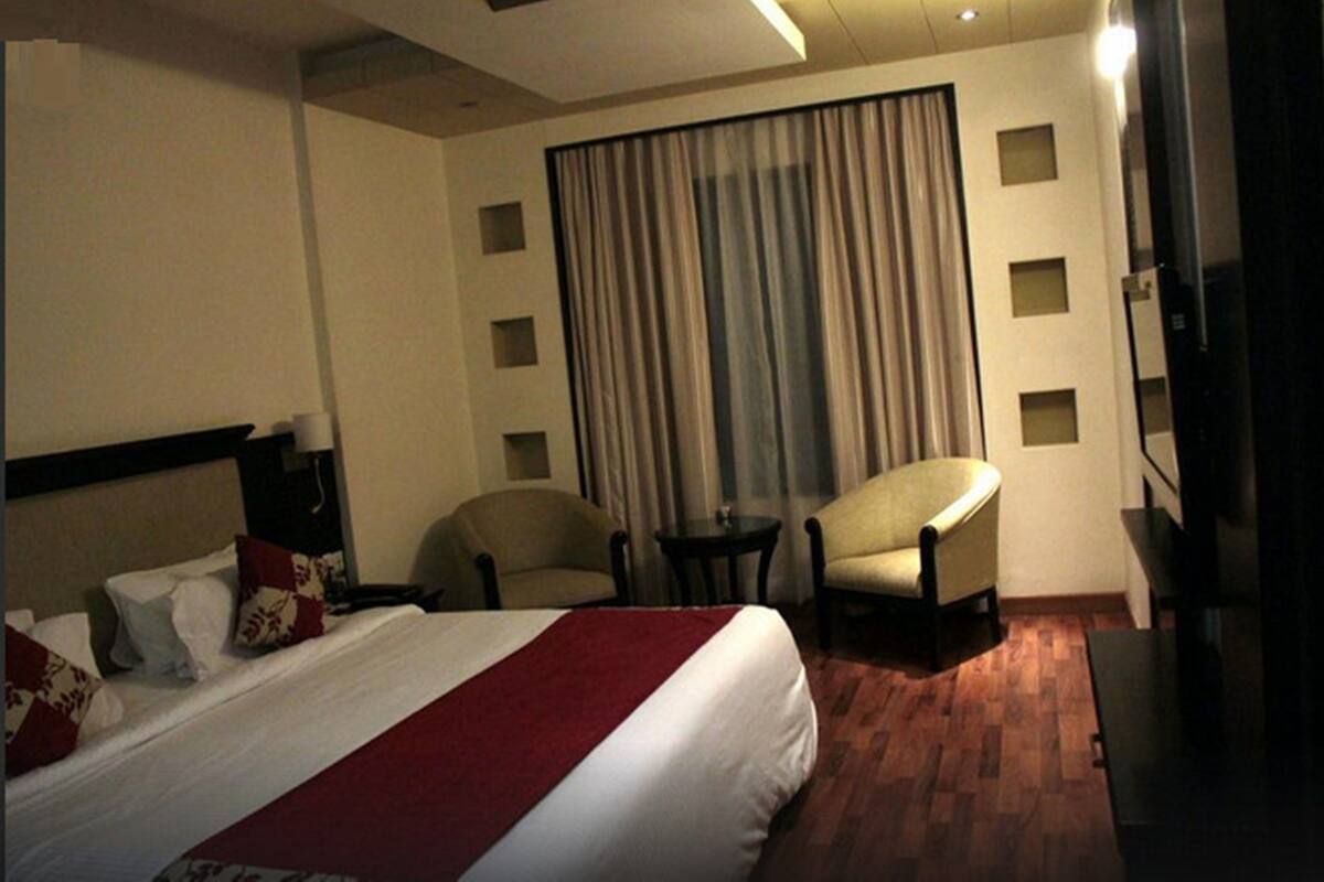 A hotel room with a large bed, two armchairs, a small table, and a TV.