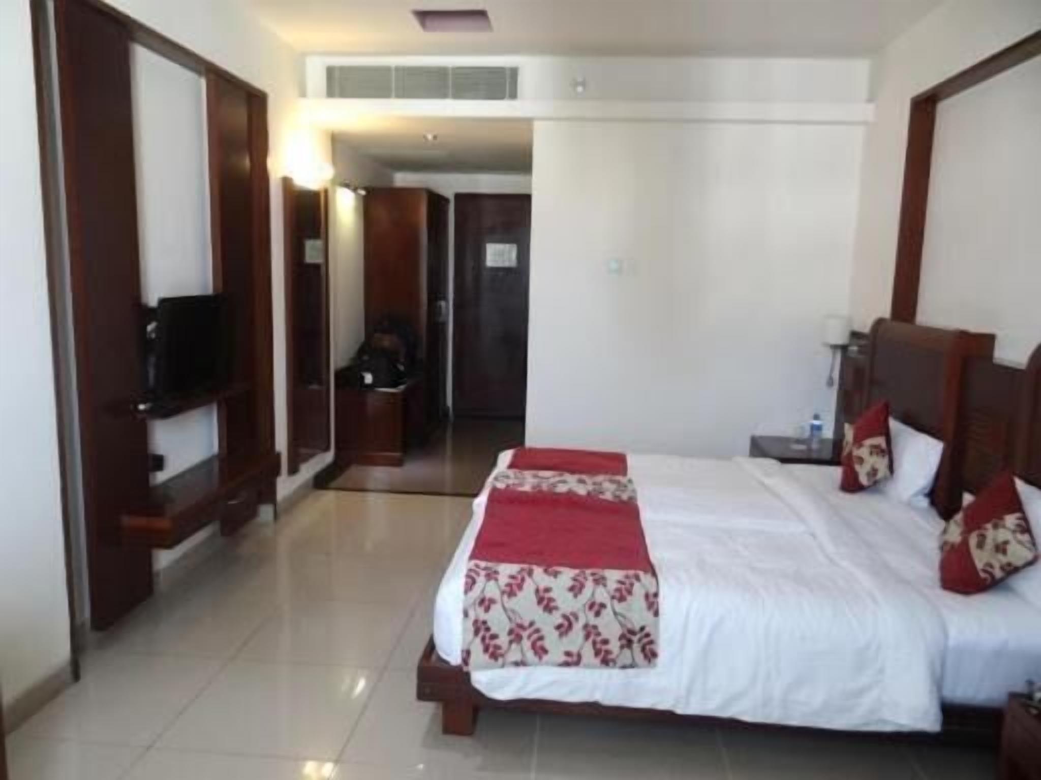 Una habitación de hotel con una cama grande, televisión y armario.