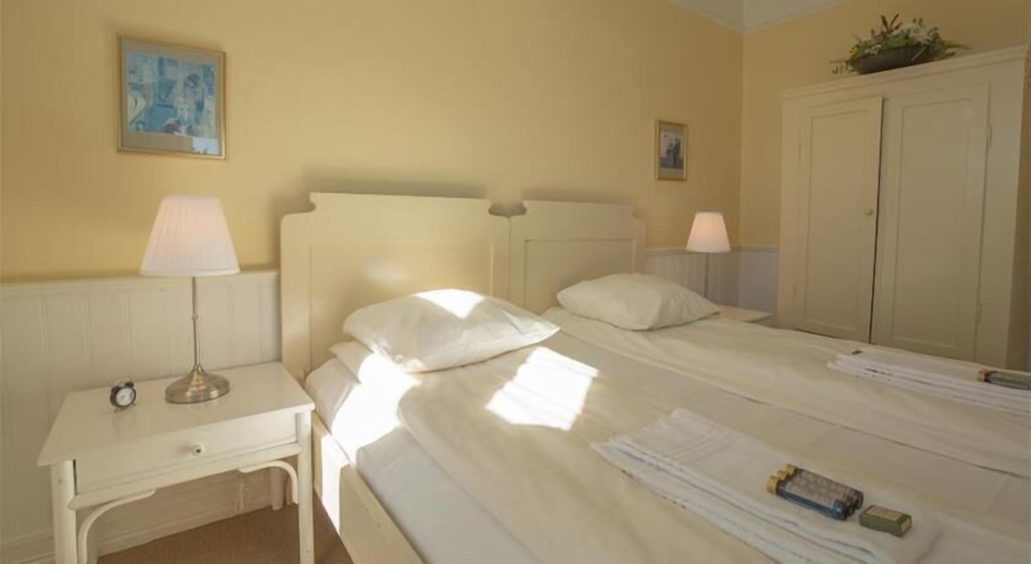 A hotel room with two beds, a desk, and a wardrobe.