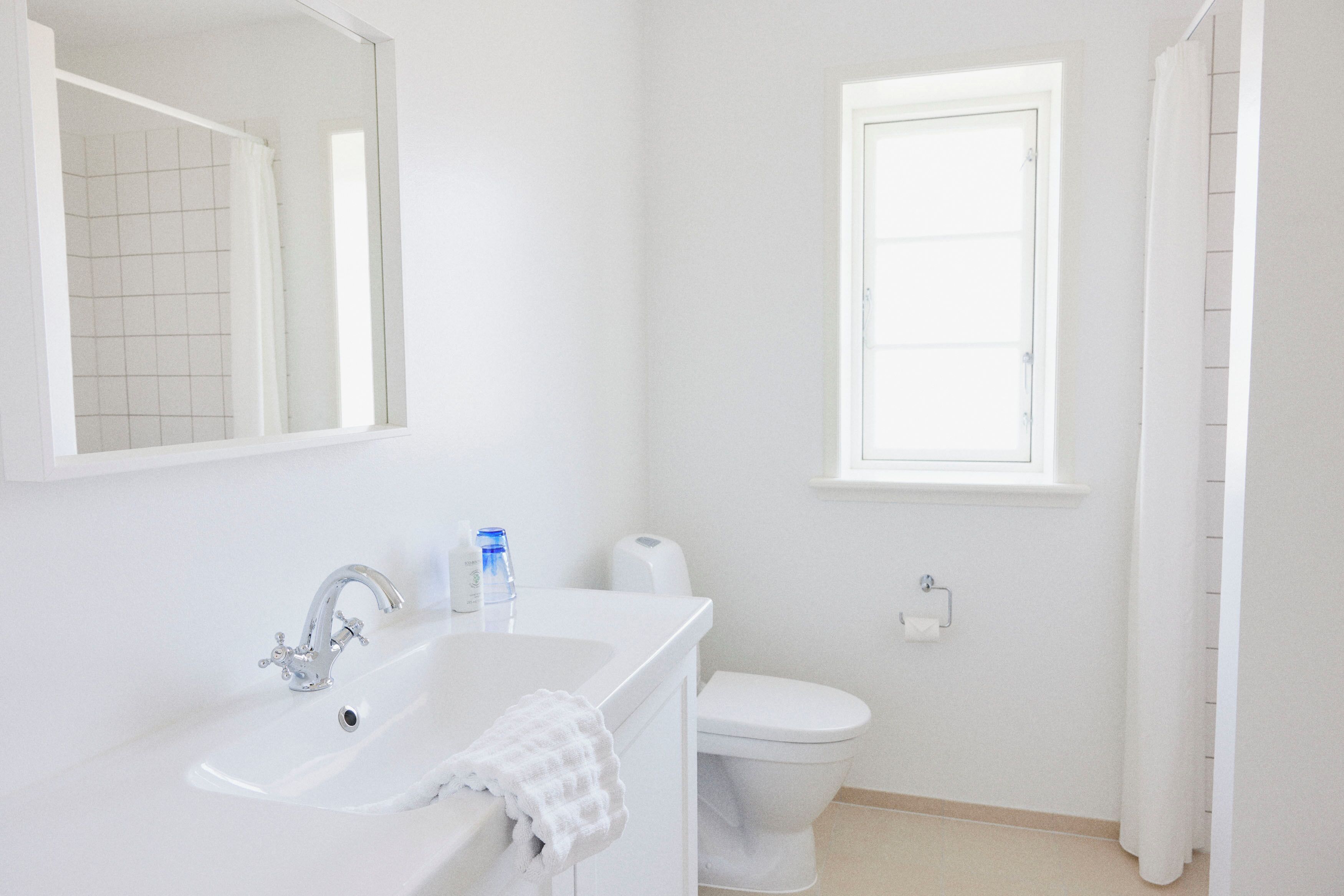 A bathroom with a white sink, a mirror, a toilet, and a window.