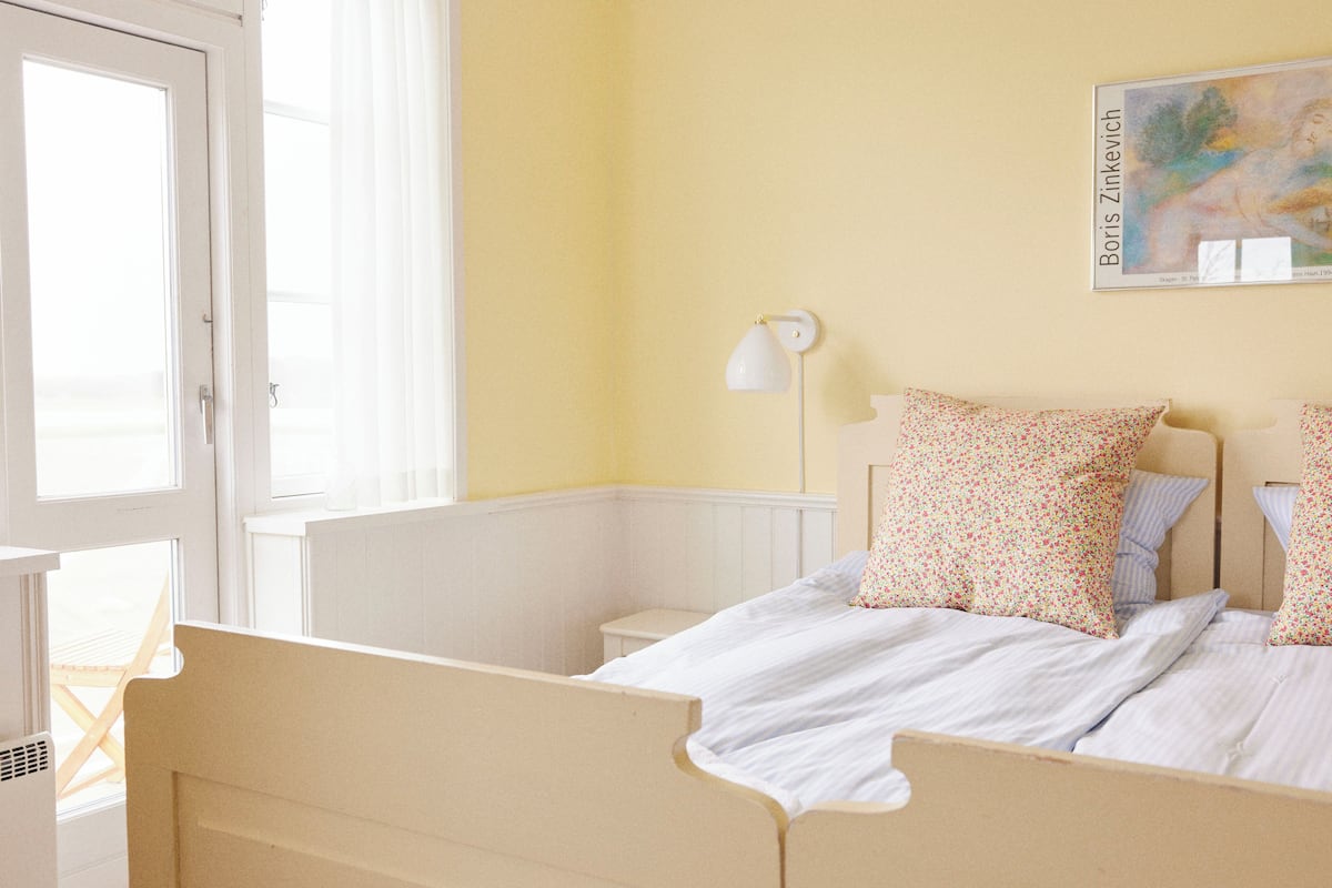 A room with a bed, a nightstand, a lamp, and a painting on the wall.