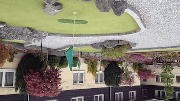A building with a green roof, hanging plants, and a stone facade.