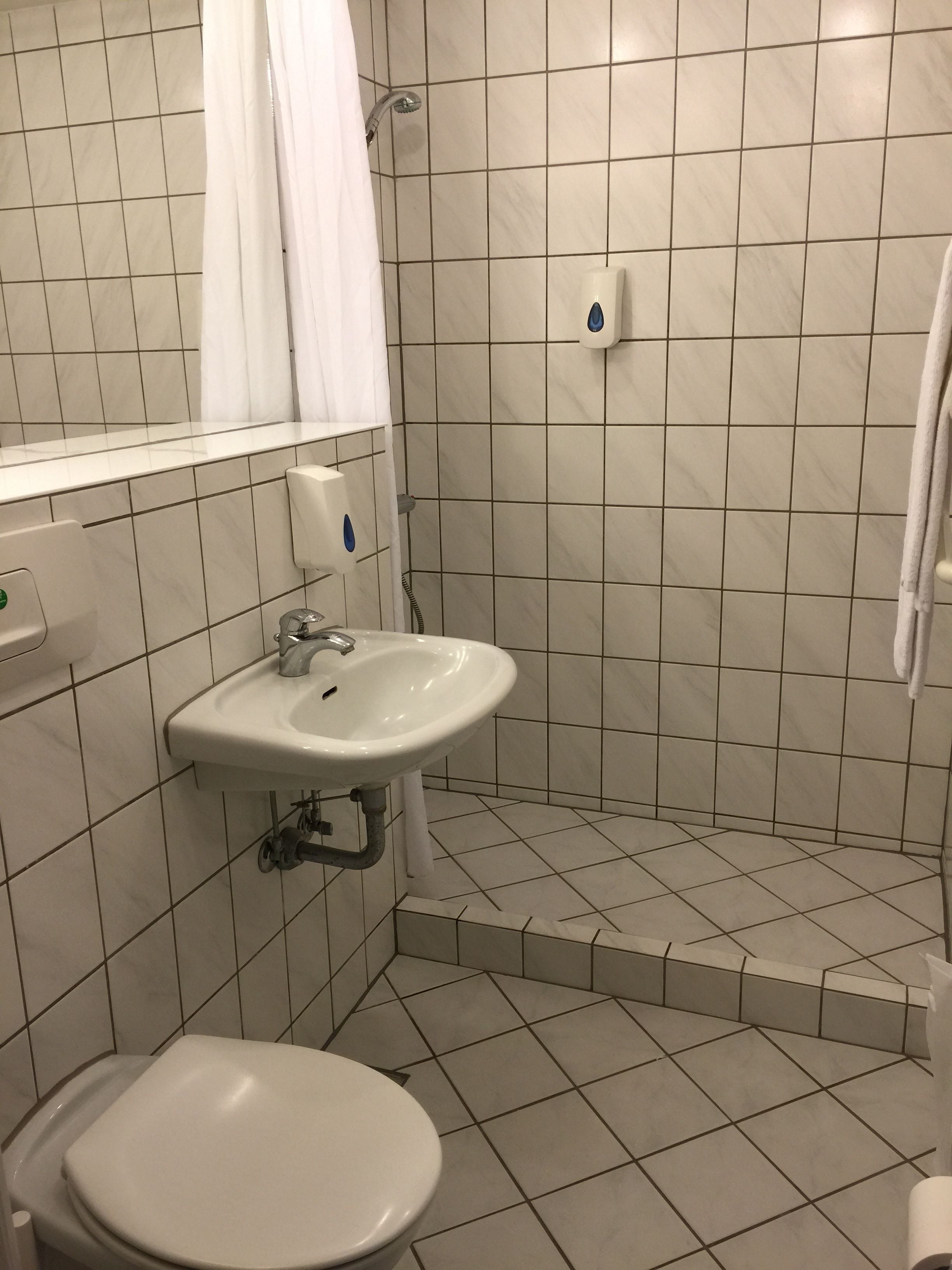 A bathroom with a white sink, toilet, and shower area.