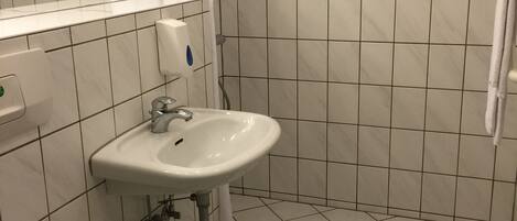 A bathroom with a white sink, toilet, and shower area.