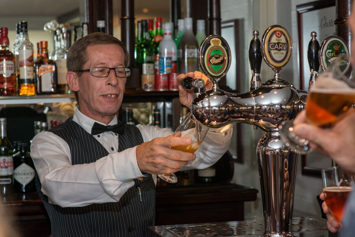 Ein Barkeeper zapft Bier aus einem Fass mit der Aufschrift 'Carlis Special' in ein Glas.