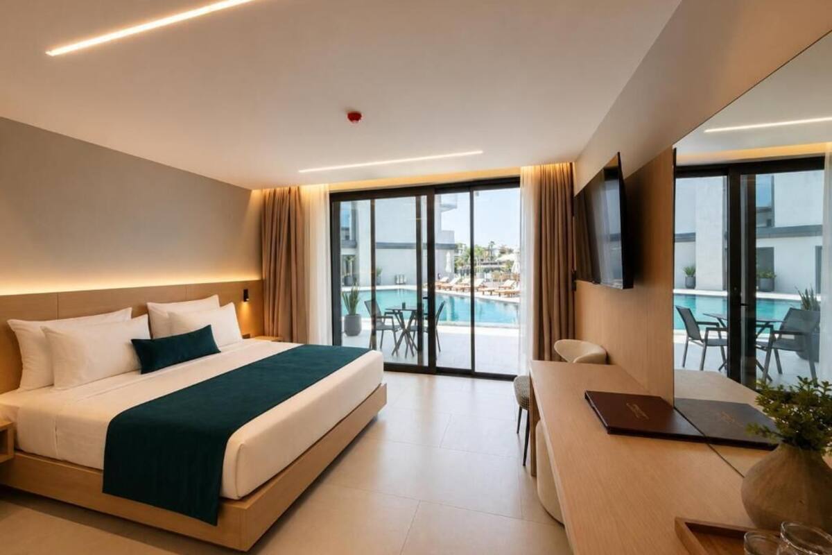 Ein modernes Hotelzimmer mit einem Bett, einem Schreibtisch und Blick auf einen Pool.