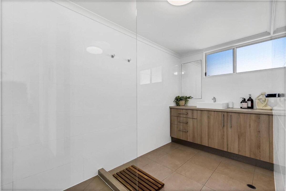 Une salle de bain moderne avec une douche, un lavabo et une fenêtre.