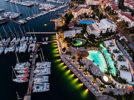 Vista aerea di un porto turistico con numerose imbarcazioni ormeggiate, una piscina e edifici circostanti.