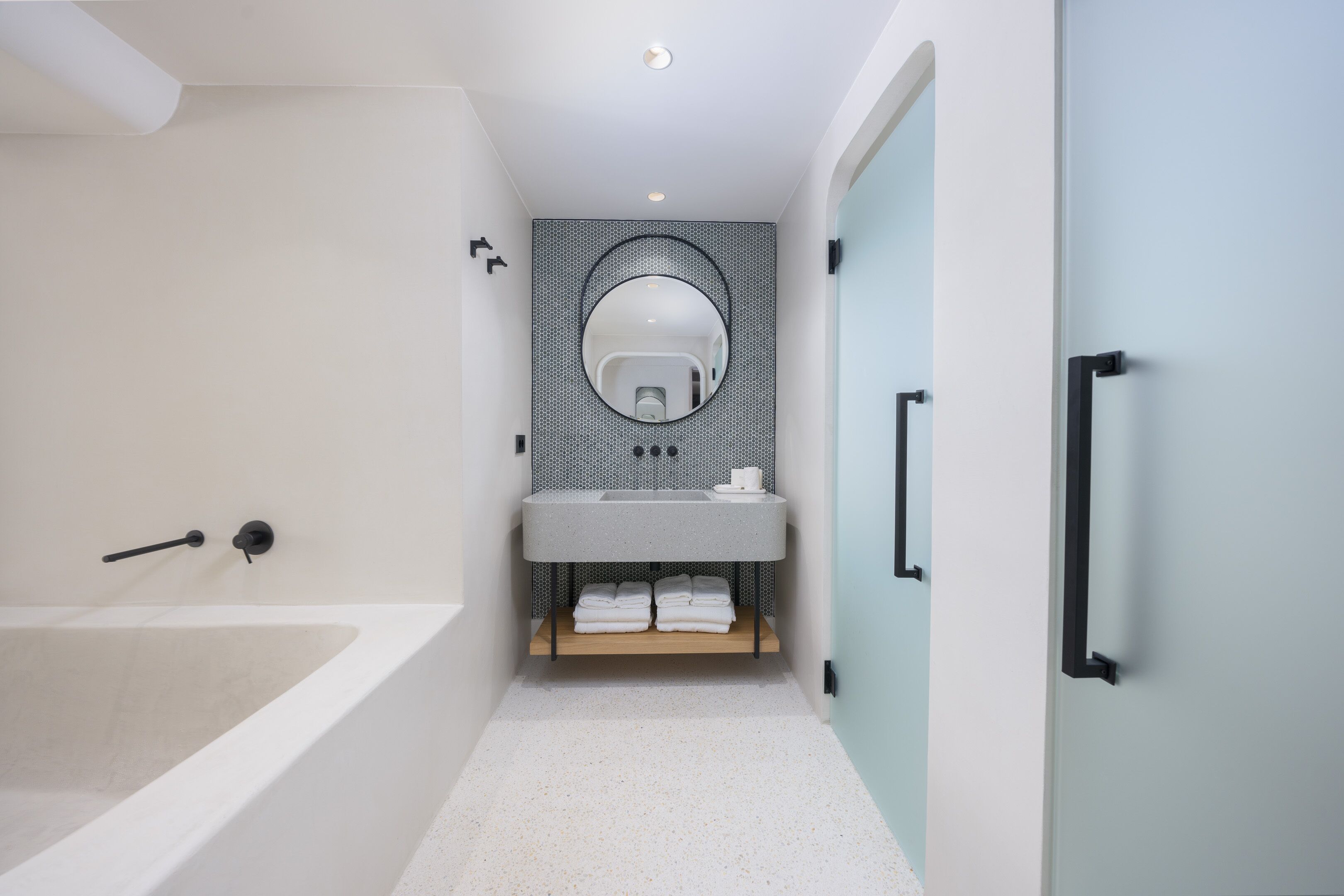 Un baño moderno con una bañera, un lavabo con espejo y un perchero para toallas.
