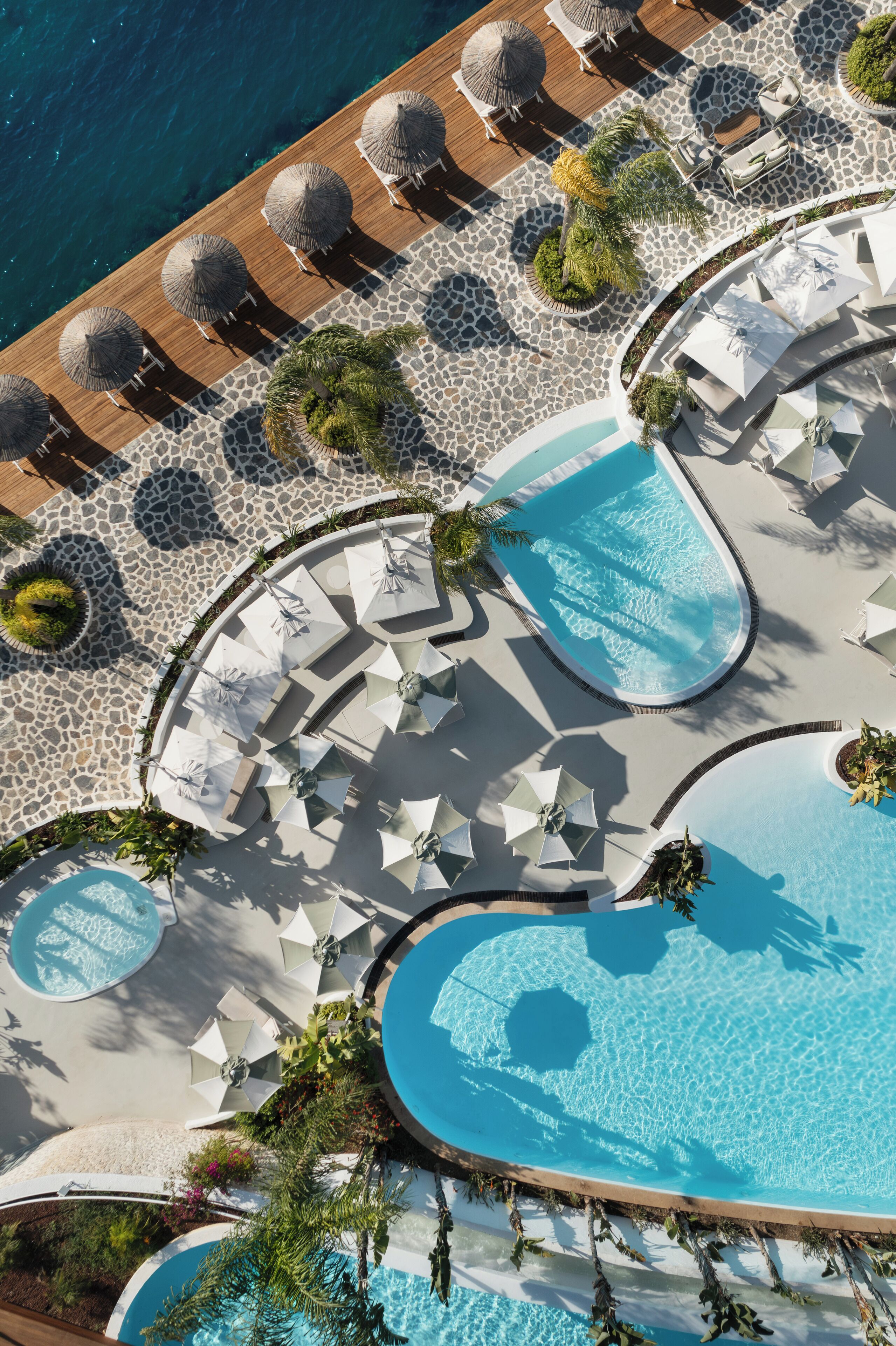 An aerial view of a resort with multiple swimming pools, sun loungers, and umbrellas.