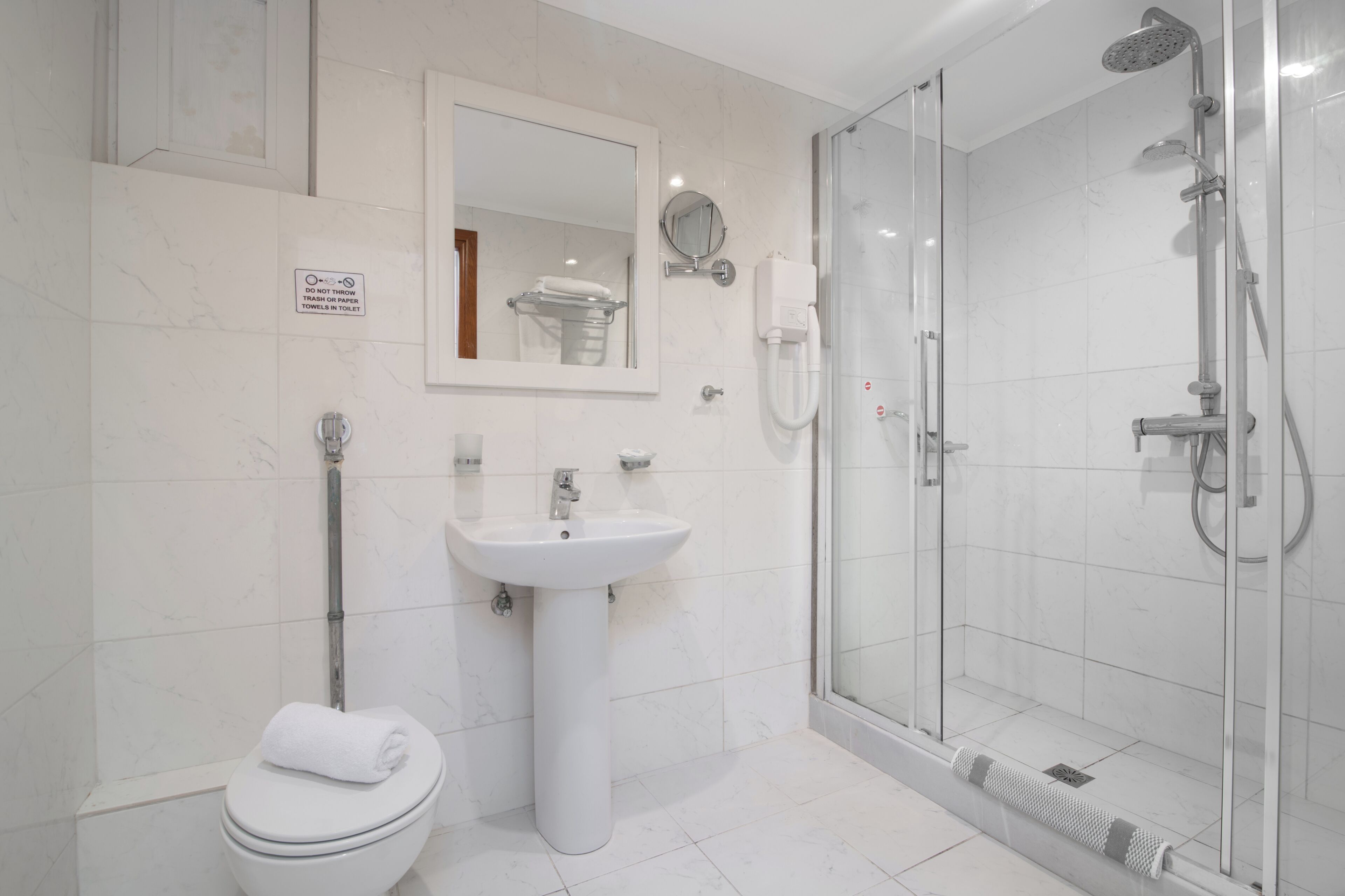 A modern bathroom with a toilet, sink, and glass-enclosed shower.