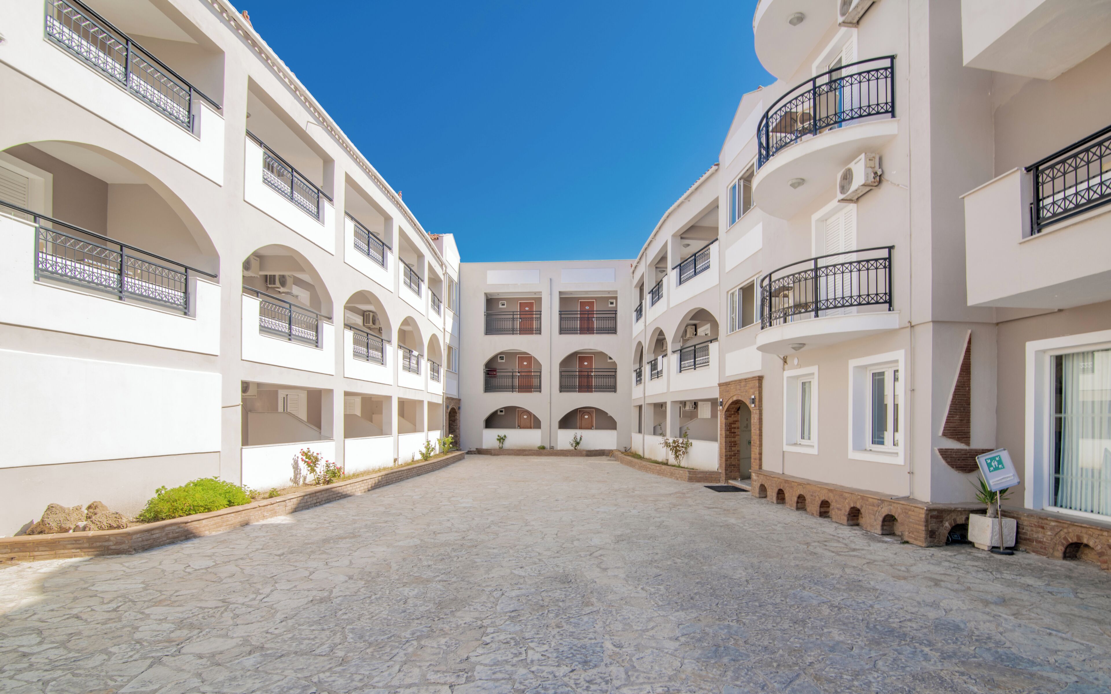 Un patio con un espacio abierto central rodeado de edificios de varios pisos con balcones y ventanas de arco.