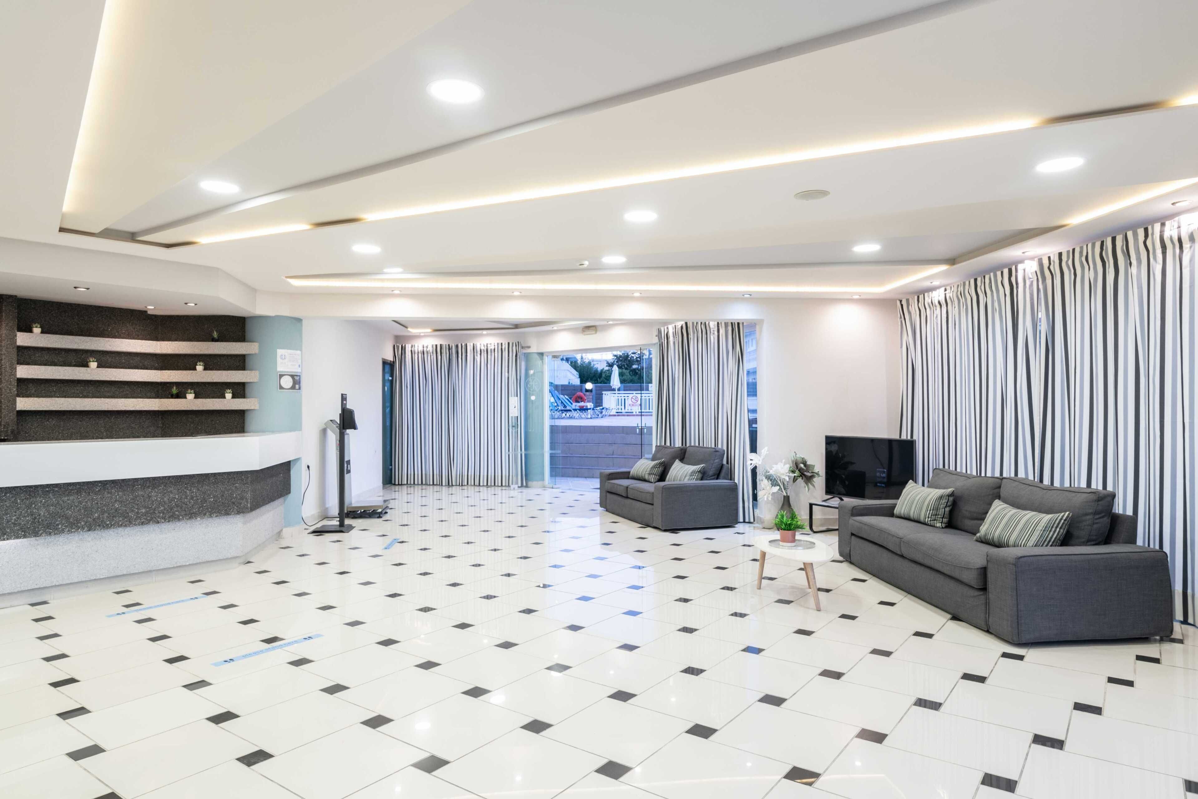A spacious lobby with a reception desk, a sofa, a television, and a patterned curtain.