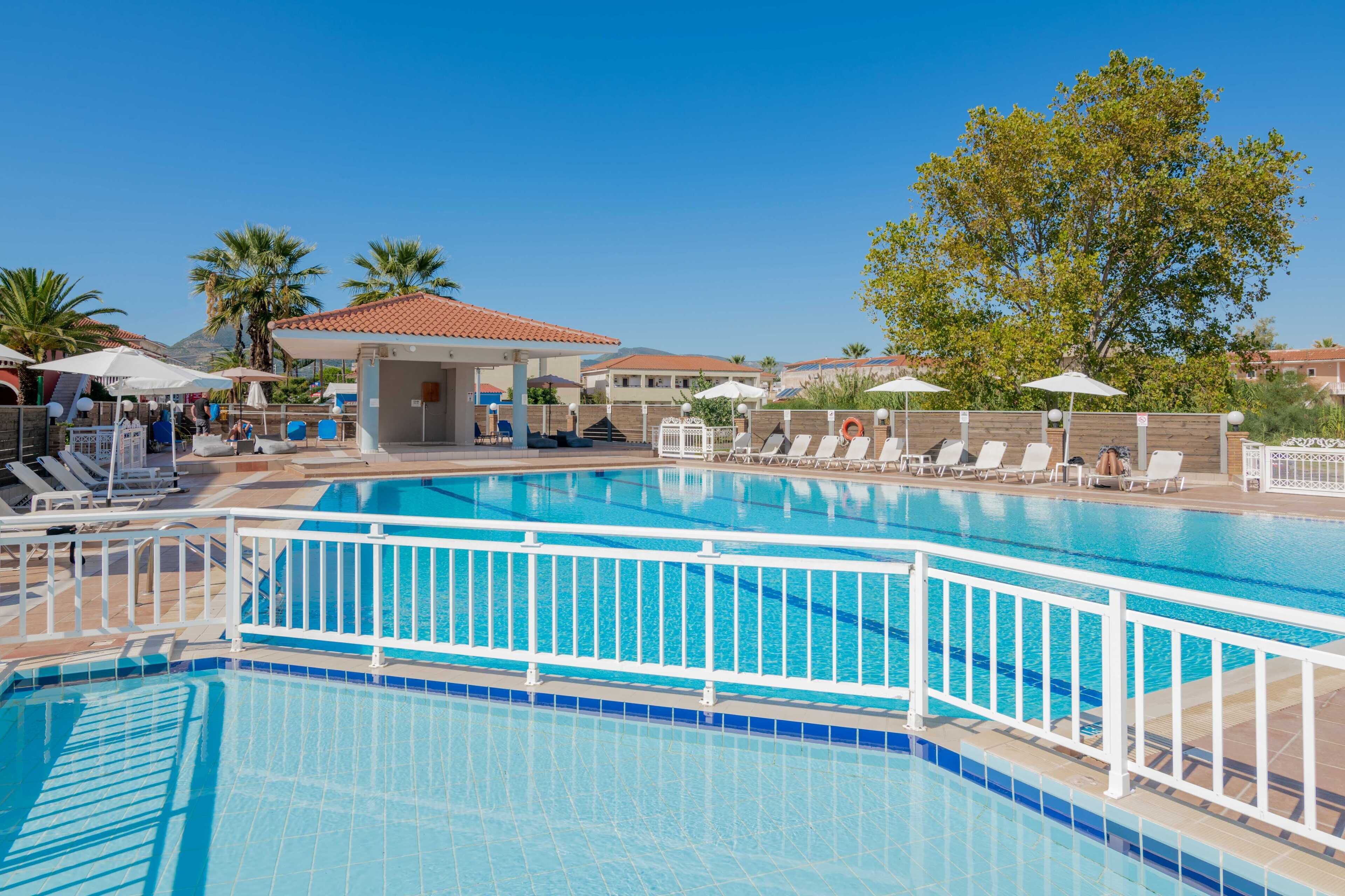 Una piscina con barandillas blancas, tumbonas y sombrillas.