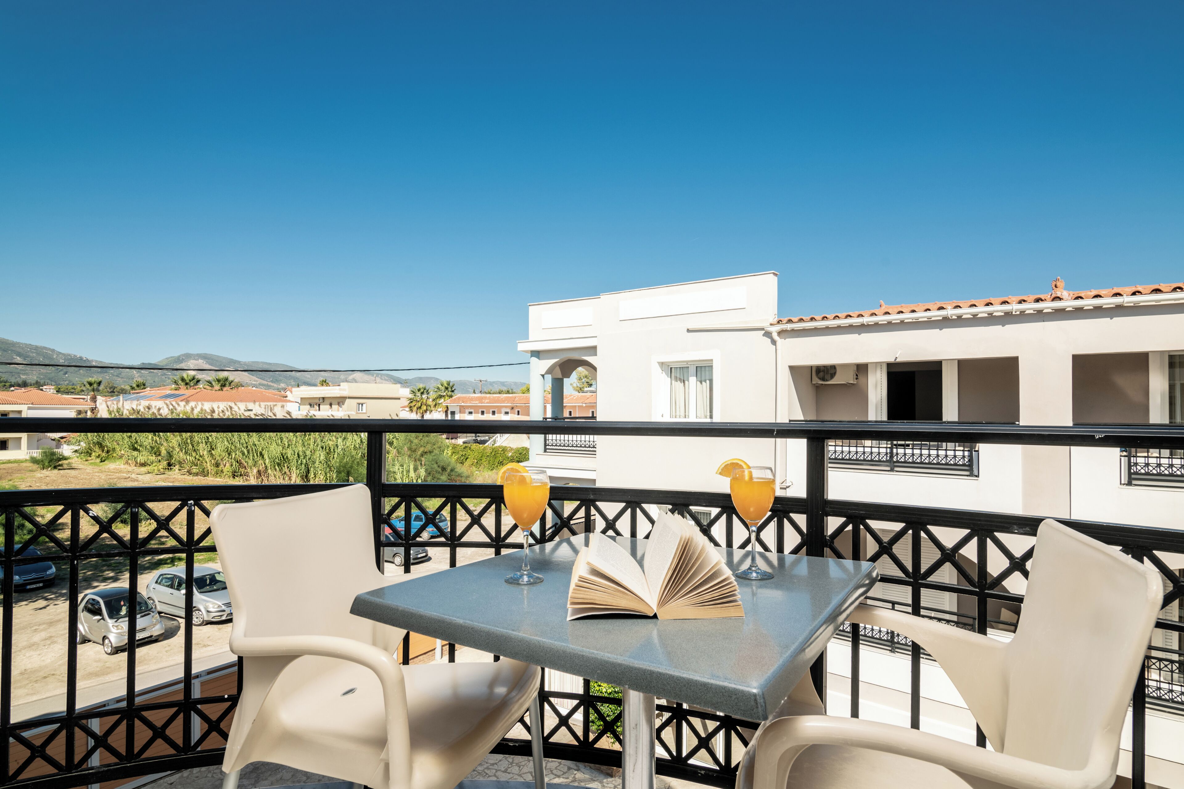 A balcony with a table, two chairs, and two drinks.