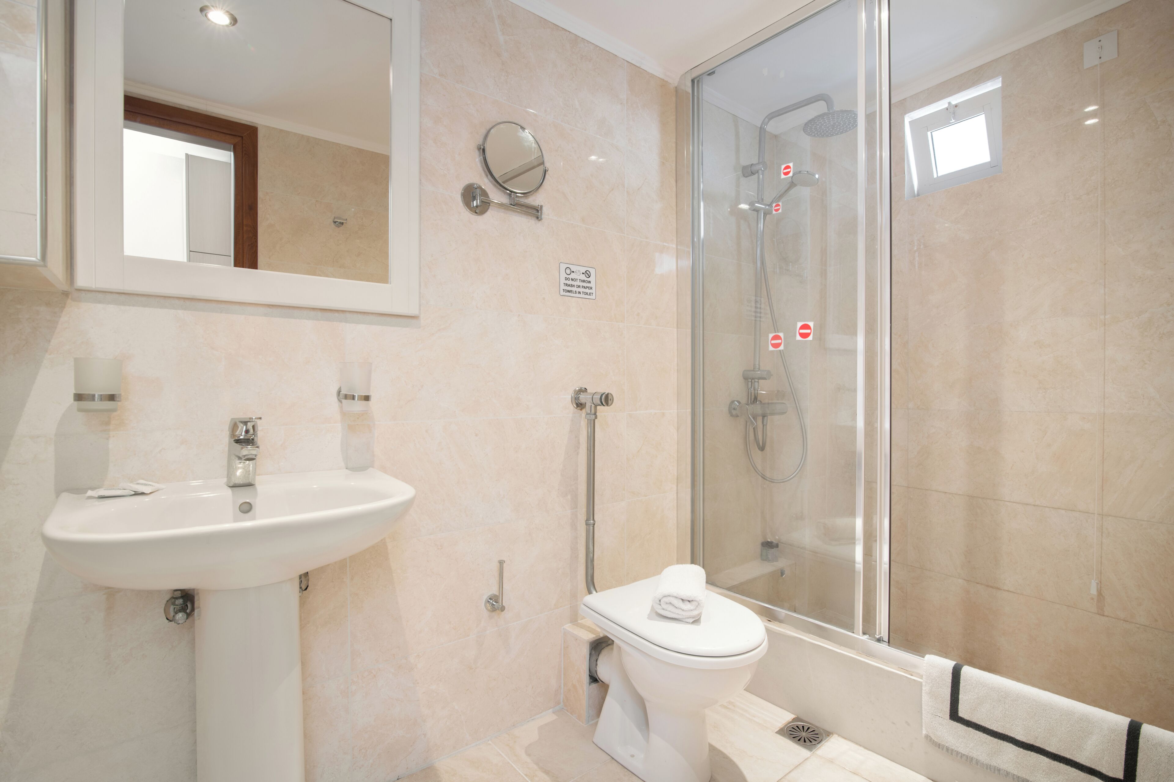 Un baño moderno con lavamanos, inodoro y ducha con mampara de vidrio.