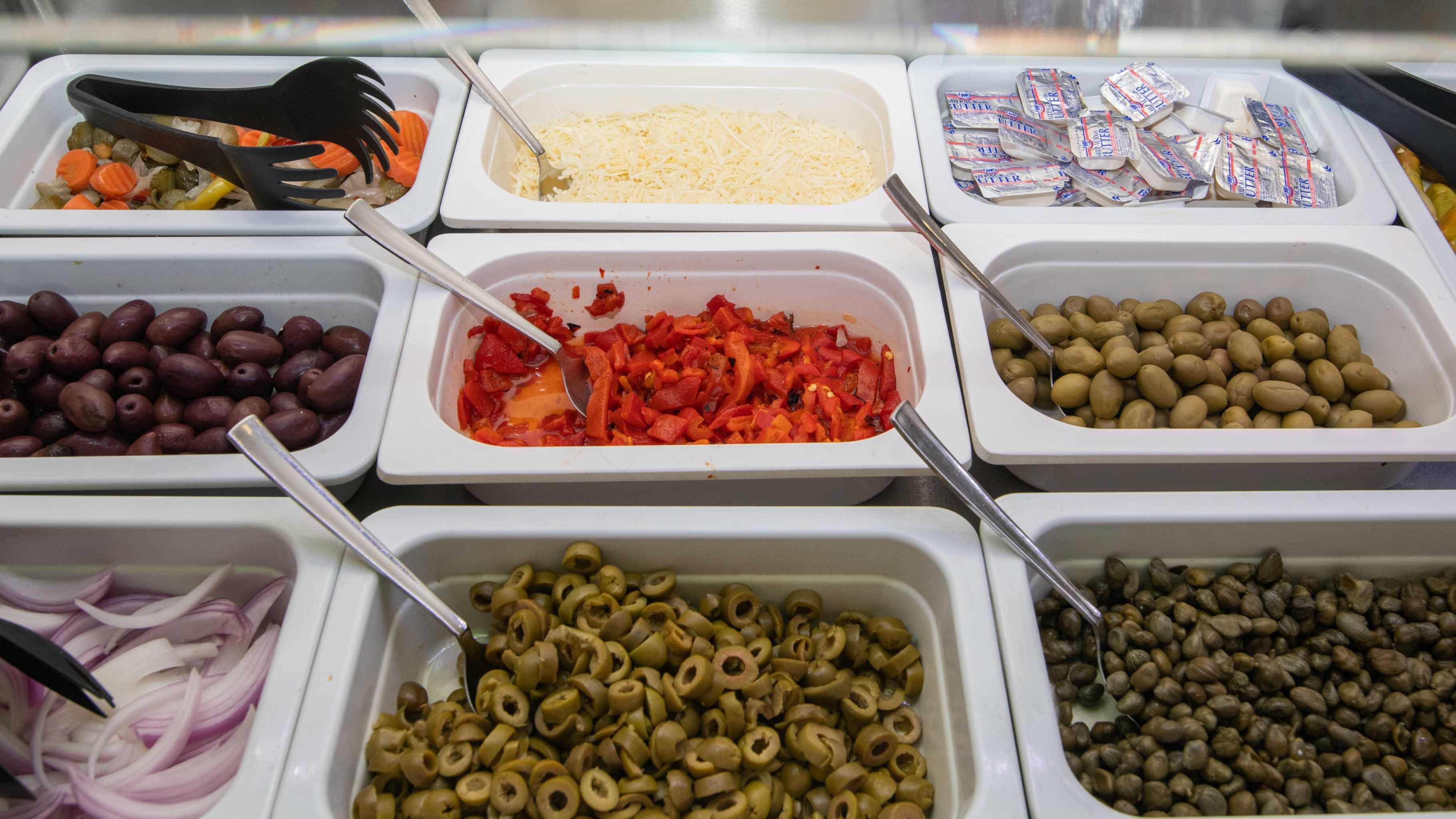 Un bufé con distintos alimentos, como aceitunas, queso y verduras en rodajas.