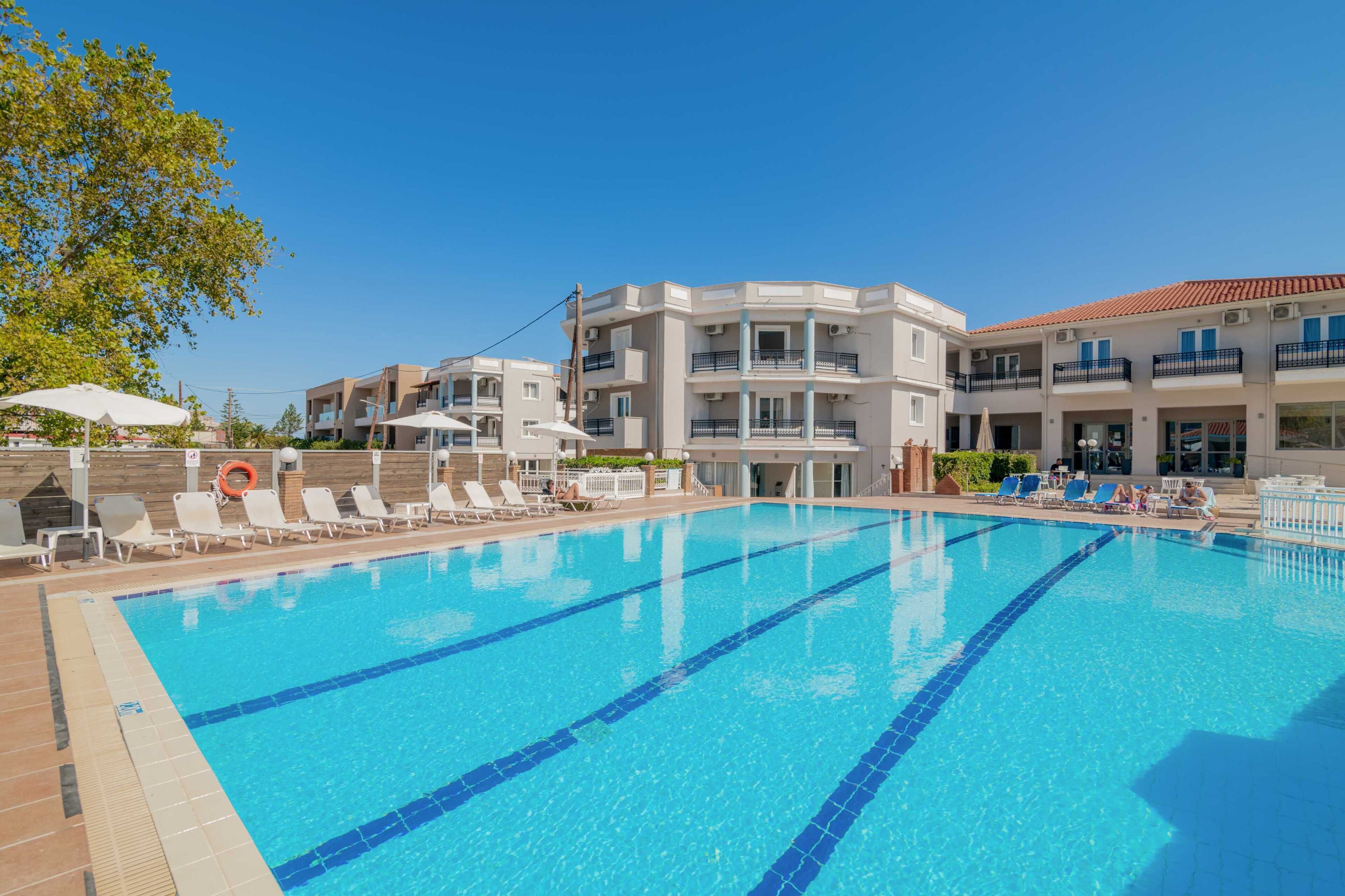 A swimming pool with clear blue water and white lounge chairs.