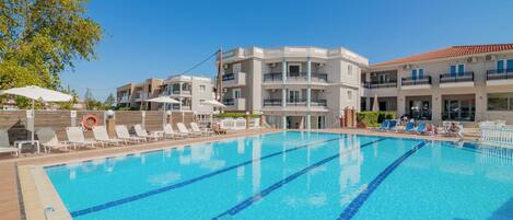 A swimming pool with clear blue water and white lounge chairs.
