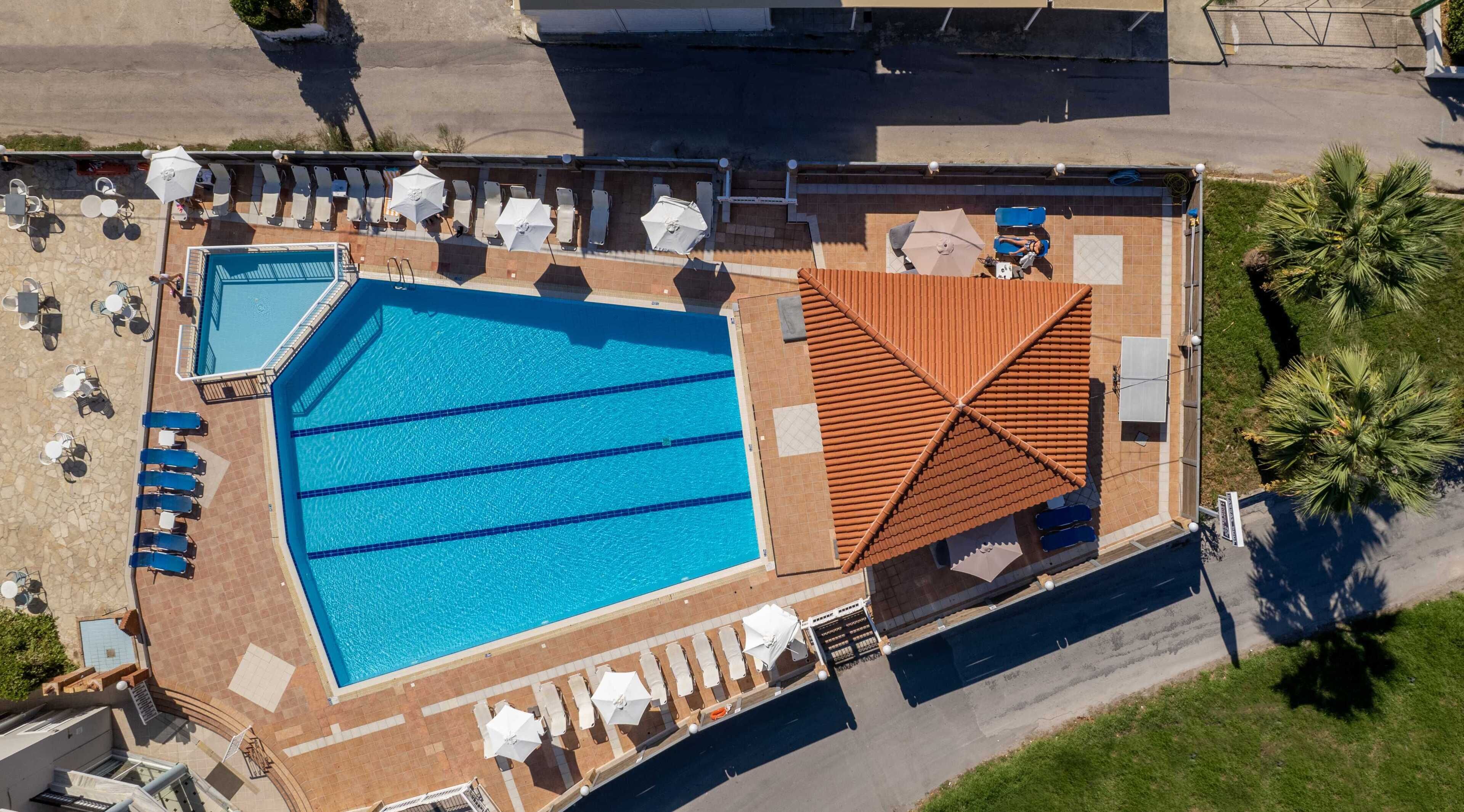 A rooftop swimming pool with multiple lanes, sun loungers, and a covered seating area.