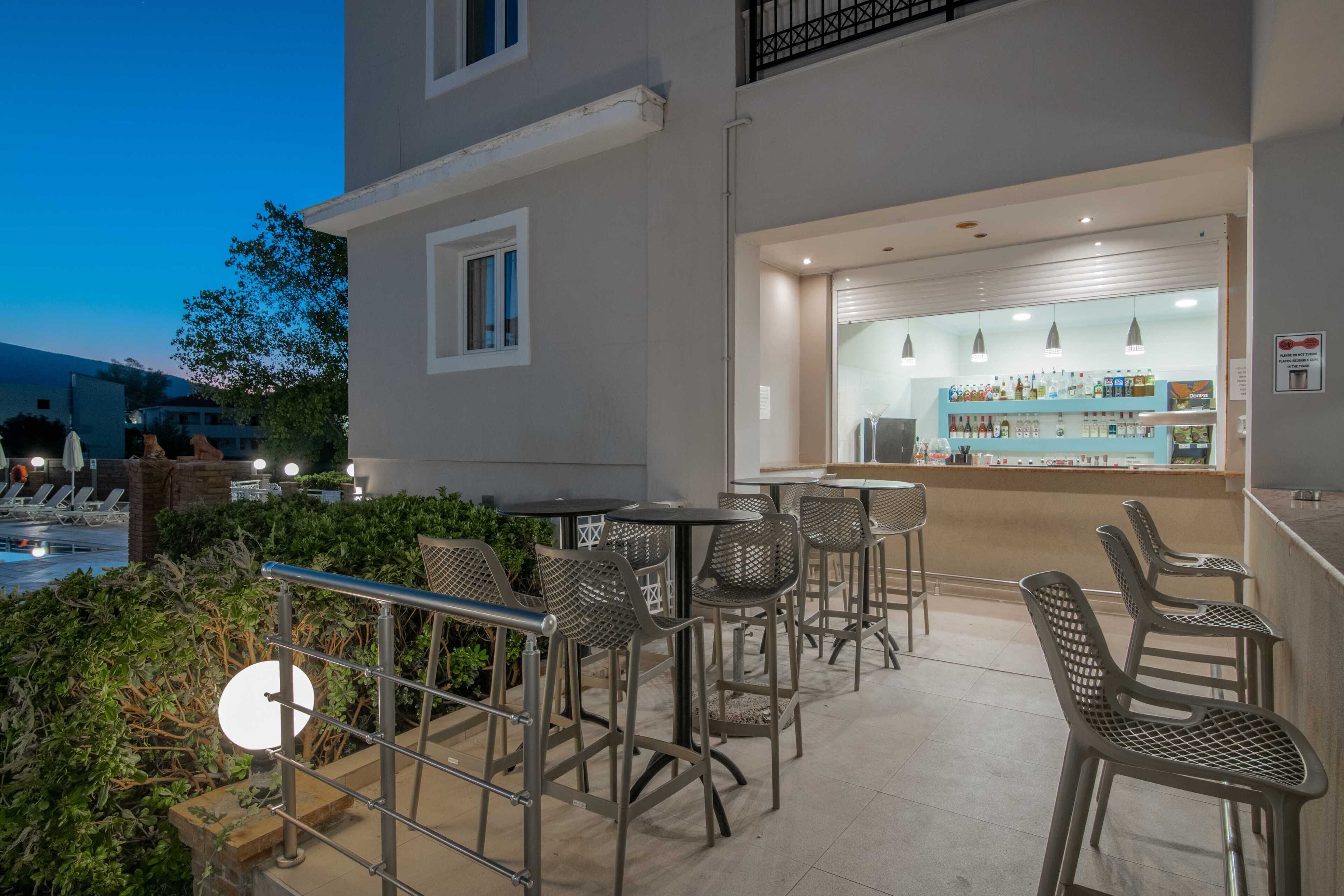 Zona de bar al aire libre con asientos y una piscina al fondo.