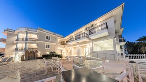 Un hôtel à plusieurs étages doté d’une terrasse et d’une cour pavée de pierres.