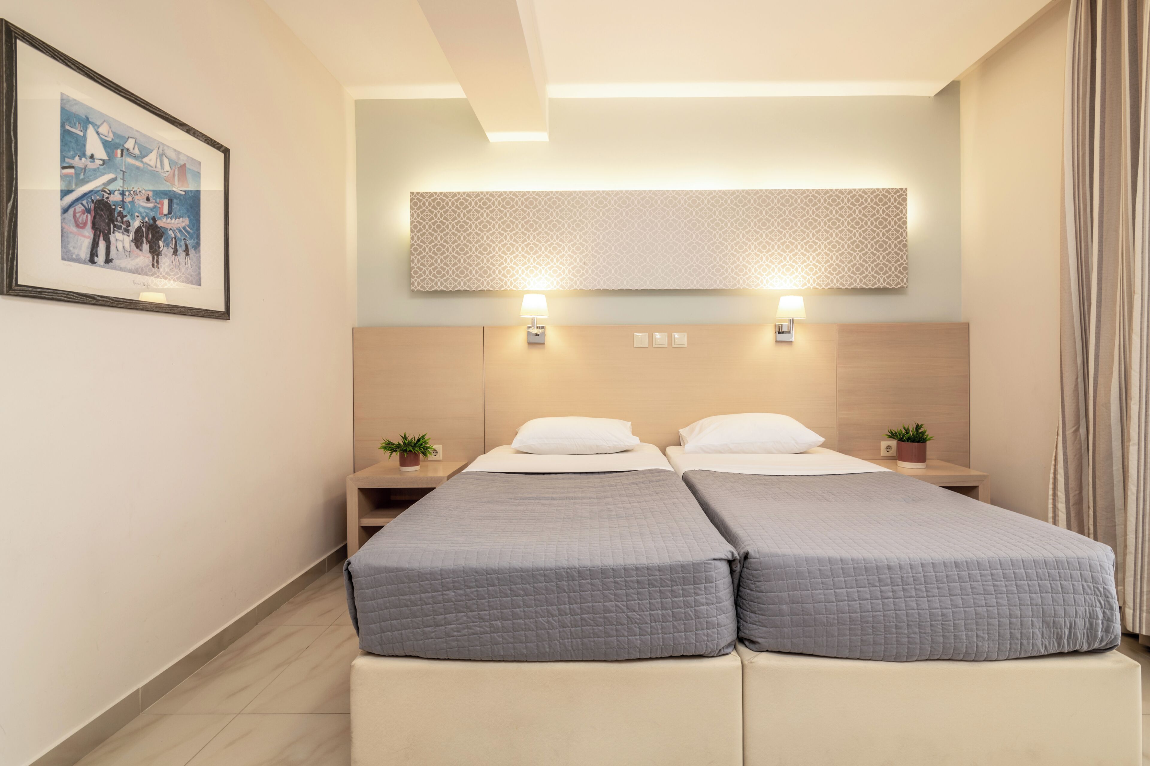 A hotel room with two beds, a large framed picture on the wall, and a patterned wall decoration above the beds.